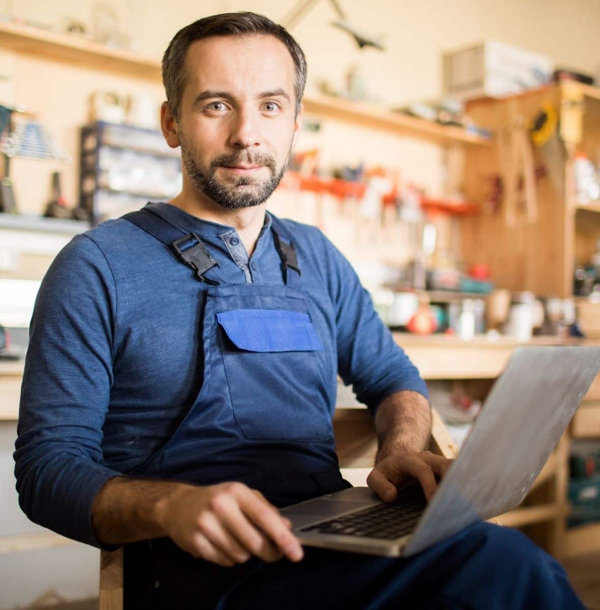 Artisan dans son atelier utilisant un ordinateur portable pour gérer son site internet professionnel et développer sa visibilité en ligne.