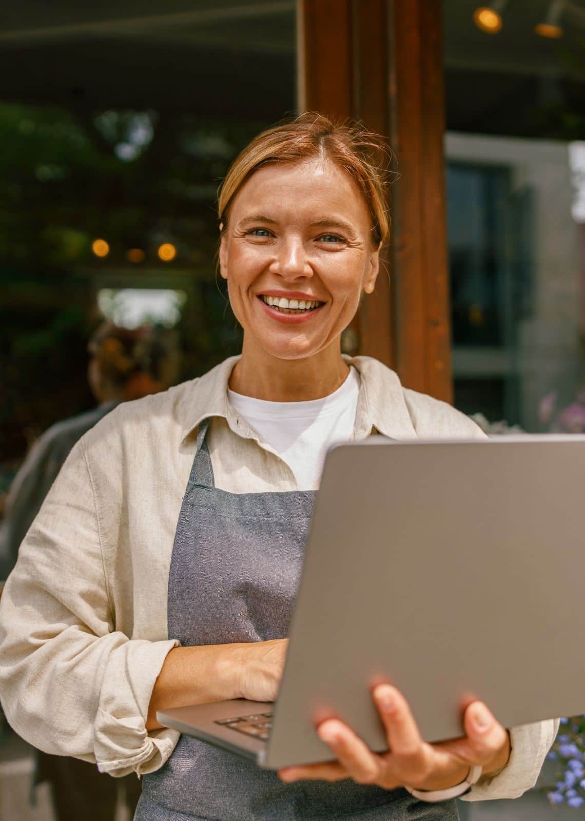 Fleuriste utilisant un ordinateur portable devant sa boutique pour développer sa visibilité en ligne et attirer des clients locaux.